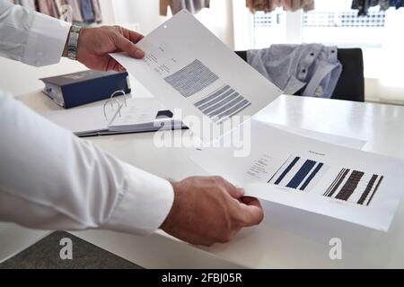 Homme mature tenant un échantillon de tissu sur la table dans la conception de vêtements studio Banque D'Images