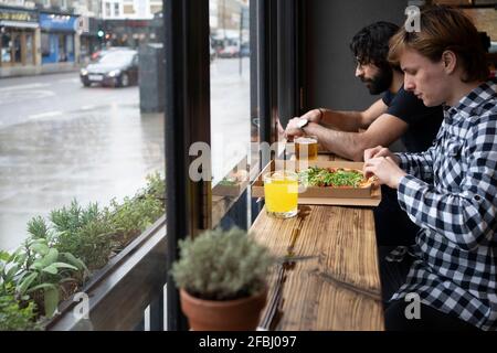 Les jeunes hommes d'affaires qui ont de la pizza et du jus de fruit assis à table bureau Banque D'Images
