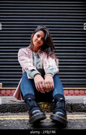 Femme souriante assise devant l'obturateur sur le sentier Banque D'Images