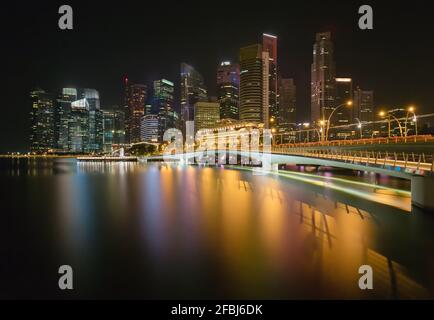 Singapour, longue exposition de Marina Bay la nuit avec Jubilee Bridge et gratte-ciels en arrière-plan Banque D'Images