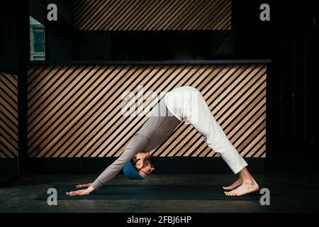 Professeur de yoga masculin pratiquant la posture du chien face vers le bas Banque D'Images