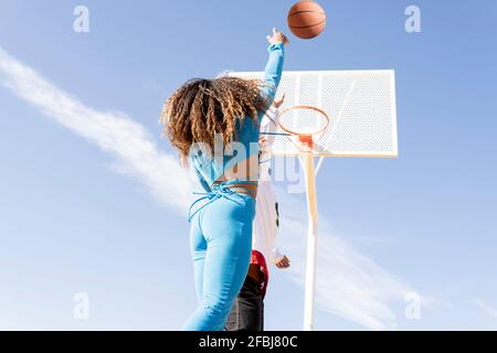 Une amie féminine filant dans un panier de basket-ball tout en jouant sur le sport cour Banque D'Images
