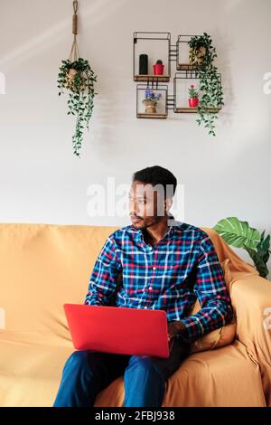Entrepreneur attentionné qui a vue sur l'extérieur tout en étant assis sur un canapé dans la salle de séjour chambre Banque D'Images
