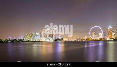 Singapour, longue exposition de Marina Bay la nuit avec l'hôtel Marina Bay Sands et Singapore Flyer en arrière-plan Banque D'Images