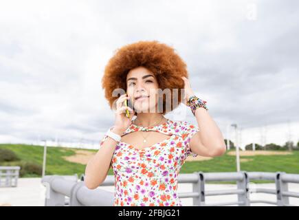 Femme avec la main dans les cheveux parlant sur le téléphone portable à stationnement Banque D'Images