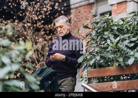 Homme mature utilisant un téléphone portable en se tenant à l'usine Banque D'Images