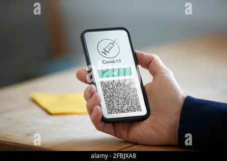 Homme tenant un smartphone avec code QR de vaccination COVID-19 Banque D'Images