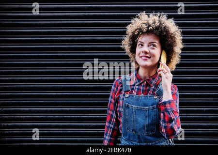 Une femme aux cheveux maus qui envisage de parler sur un téléphone portable Banque D'Images