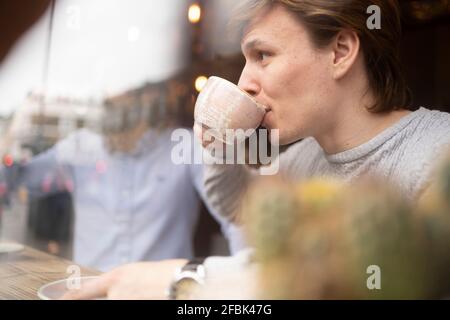 Beau homme d'affaires ayant un café dans le bureau vu à travers le verre Banque D'Images