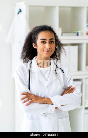 Jeune femme médecin avec les bras croisés debout dans la clinique Banque D'Images