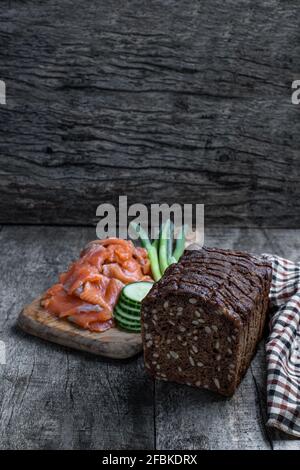 Pain de seigle aux graines et saumon fumé sur bois rustique tableau Banque D'Images