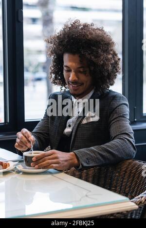 Homme d'affaires de race mixte mélangeant café dans café Banque D'Images