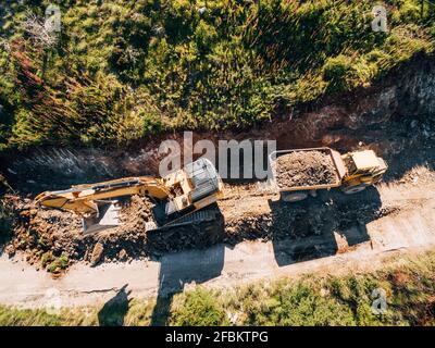 Un tracteur à chenilles jaune charge un véhicule de carrière avec du sable. Vue aérienne Banque D'Images