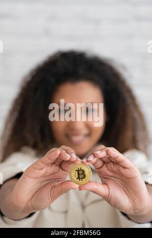 Jeune femme souriante tenant un bitcoin d'or Banque D'Images