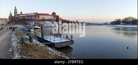 Cracovie, Pologne - 20 mars 2021 : prise de vue en grand angle d'un château de wawel et personnes marchant dans une rue à côté de la vistule pendant un peu de neige sur le Banque D'Images