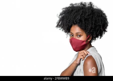 un adolescent noir portant un masque de protection contre le covid-19 avec un sourire sur son visage montre la marque du vaccin, isolée sur fond blanc Banque D'Images