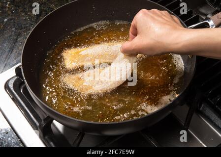 Faire frire à la poêle ou faire cuire à la maison du filet de poisson sur une cuisinière. Banque D'Images