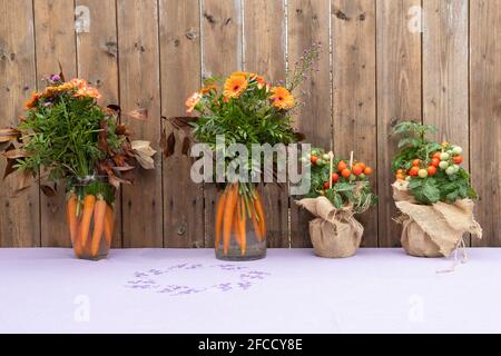 Bio bio bio design original bouquet avec des fleurs et des carottes et Tomates cerises mûres poussant dans UN pot sur une table Banque D'Images