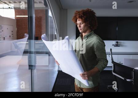 Homme d'affaires de race mixte dans la salle de réunion debout et regardant document blueprint Banque D'Images