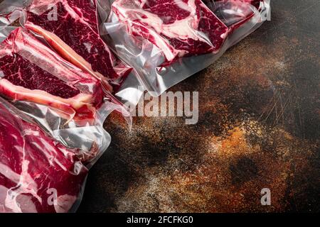 Steak de bœuf scellé sous vide prêt pour la cuisson sous vide, tomahawk, t-bone, steak de club, entrecôtes d'oeil et de filet, sur fond rustique foncé ancien, wi Banque D'Images