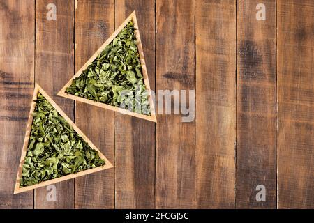 Feuilles de moringa séchées dans un bol triangulaire - Moringa oléifera Banque D'Images