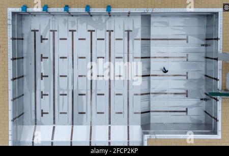 Bad Soden am Taunus, Allemagne. 19 avril 2021. Un employé de la piscine traverse la piscine vide de la piscine extérieure de Bad Soden (vue aérienne avec un drone). Le début de la saison de la piscine extérieure cette année n'a pas encore été déterminé en raison de Corona. Normalement, la plupart des piscines sont ouvertes le 1er mai. Actuellement, les villes mettent leurs piscines extérieures en état de fonctionnement. Les travaux de rénovation nécessaires ont été achevés en hiver. Crédit : Boris Roessler/dpa/Alay Live News Banque D'Images