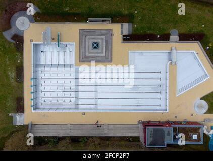 Bad Soden am Taunus, Allemagne. 19 avril 2021. Un employé de la piscine traverse la piscine vide de la piscine extérieure de Bad Soden (vue aérienne avec un drone). Le début de la saison de la piscine extérieure cette année n'a pas encore été déterminé en raison de Corona. Normalement, la plupart des piscines sont ouvertes le 1er mai. Actuellement, les villes mettent leurs piscines extérieures en état de fonctionnement. Les travaux de rénovation nécessaires ont été achevés en hiver. Crédit : Boris Roessler/dpa/Alay Live News Banque D'Images