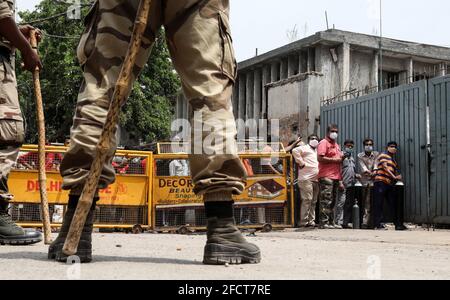 New Delhi, Inde. 23 avril 2021. Les membres de la famille font la queue pour remplir des bouteilles d'oxygène vides tandis qu'un personnel de sécurité se tient sur la garde à l'extérieur du centre de remplissage d'oxygène de New Delhi. L'Inde est à court d'oxygène pendant la deuxième vague de la pandémie de Covid-19. L'Inde a enregistré 332,730 nouveaux cas de Covid-19 en une seule journée et 2,263 décès au cours de la dernière journée. Crédit : SOPA Images Limited/Alamy Live News Banque D'Images