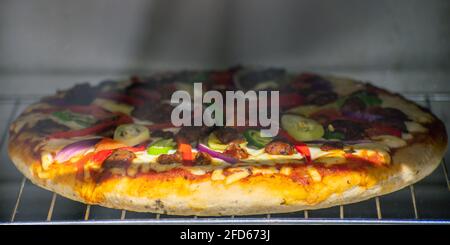 Pizza épicée au poulet dévoré à l'intérieur d'un four, délicieux dîner de boulangerie fait maison. Poulet et poivron dévorés et tomates oignons et mozzarella Banque D'Images
