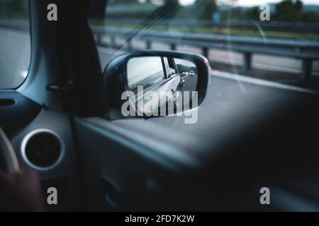 Rétroviseur extérieur et lumière du soleil du soir depuis la carrosserie de la voiture et lueur sur l'autoroute. Concept automobile à mouvement rapide. Vue sur le rétroviseur extérieur Banque D'Images