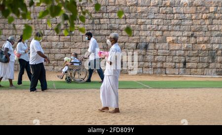 Anuradhapura, Sri Lanka - 03 31 2021: Vieille dame en fauteuil roulant avec des offrandes de fleurs et son fils emmène sa mère à Jaya Sri Maha Bodhi pour adorer. Banque D'Images