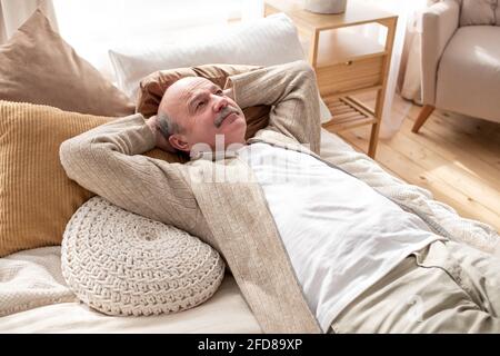 Homme hispanique senior reposant à la maison dormant au lit. Grand-père ayant une sieste. Banque D'Images