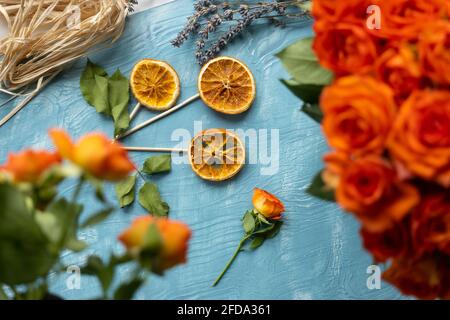 Une fleur faite de tranches d'orange séchées avec une rose d'orange fleurs de lavande sur fond de bois bleu Banque D'Images