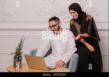 Le couple musulman en vêtements nationaux communique par communication vidéo. Vidéoconférence avec des amis Banque D'Images
