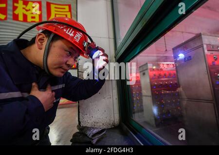 (210424) -- TAIYUAN, 24 avril 2021 (Xinhua) -- Zhang Shiqi se prépare à pénétrer dans un tunnel minier à la mine de du'erping du groupe de charbon Shanxi Coking, dans la province de Shanxi, au nord de la Chine, le 18 mars 2021. Zhang Lianggui, son fils Zhang Hai et son petit-fils Zhang Shiqi avaient tous travaillé comme mineurs de charbon. L'histoire de cette famille de mineurs de charbon sur trois générations illustre l'essor de l'industrie minière chinoise, de l'activité humaine à celle de la technologie. Près de 90 ans, Zhang Lianggui est un mineur à charbon à la retraite. Recruté en 1954, il rappelle les conditions de travail difficiles des mineurs de charbon dans la da Banque D'Images