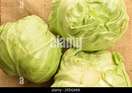 Trois têtes de chou vert vif parfumées sur un tissu jute, gros plan, vue du dessus. Banque D'Images