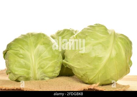 Trois têtes de chou vert vif parfumées sur un tissu de jute, gros plan, sur un fond blanc. Banque D'Images