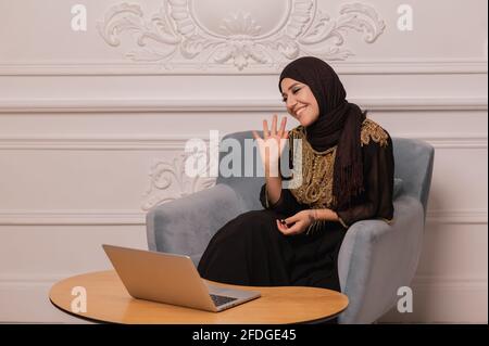 Une jeune femme musulmane confiante regarde la vidéo de conférence par webcam à la maison Banque D'Images