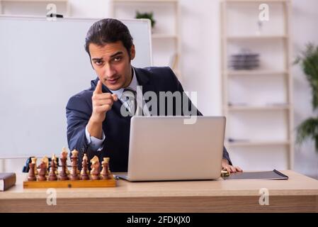 Un jeune homme d'affaires joue aux échecs sur le lieu de travail Banque D'Images