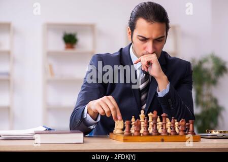 Un jeune homme d'affaires joue aux échecs sur le lieu de travail Banque D'Images