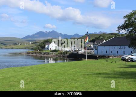 Distillerie Talisker sur l'île de Skye avec les montagnes Cuilin en arrière-plan. Banque D'Images