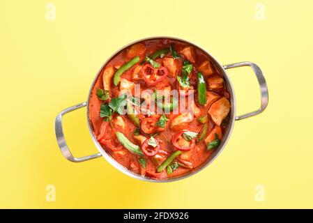 Curry de poulet rouge de style thaïlandais avec légumes dans une casserole sur fond jaune. Vue de dessus, plan d'appartement Banque D'Images