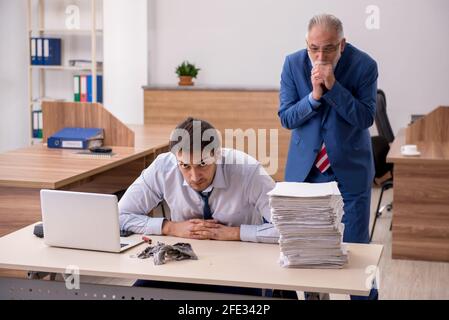 Un employé et son vieux patron brûlent des papiers sur le lieu de travail Banque D'Images