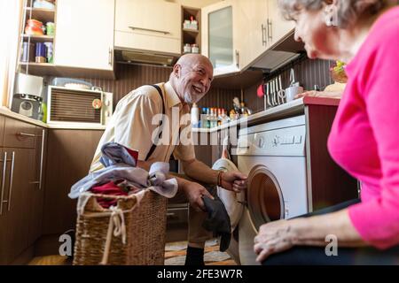 Homme senior faisant la lessive à la maison Banque D'Images