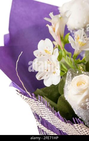 Bouquet de fleurs dans un emballage violet gros plan. Roses blanches et alstroemeria blanche dans un luxueux bouquet. Banque D'Images