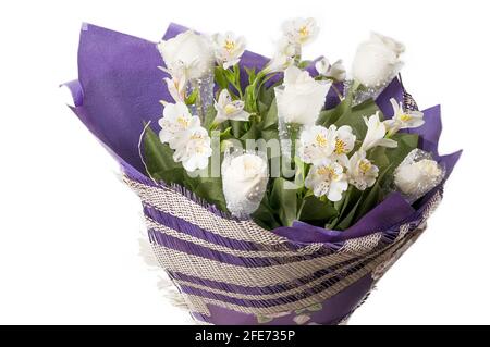 Bouquet de fleurs dans un emballage violet gros plan. Roses blanches et alstroemeria blanche dans un luxueux bouquet. Banque D'Images