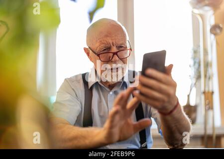 Prise de vue d'un homme âgé utilisant un téléphone portable à accueil Banque D'Images