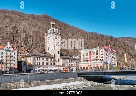 Sotchi, Russie - 4 mars 2020 : station de ski Rosa Khutor. Vue sur la rivière Mzymta et l'hôtel de ville avec horloge sur la place Rosa. Paysage urbain Banque D'Images