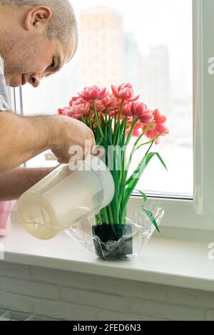 un homme arroser un bouquet de fleurs fait avec une éponge. Banque D'Images