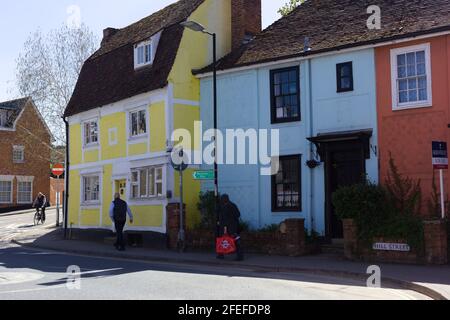 Vue sur la rue d'un cycliste et de deux hommes marchant le long d'une rangée de propriétés et maisons d'époque colorées le long de Hill Street, Saffron Walden, Essex, Britai Banque D'Images